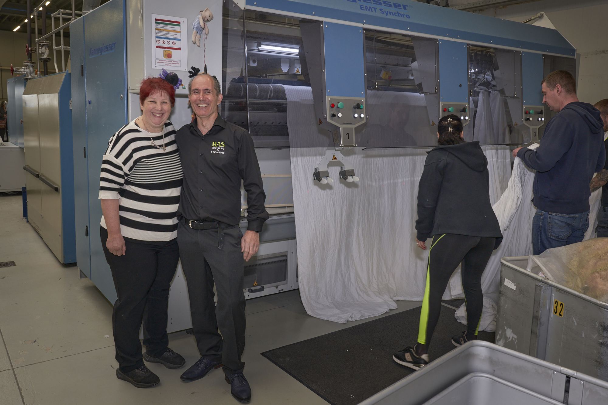 Madelon en Sander Brandt met medewerkers bij de mangel van RAS Wasserij